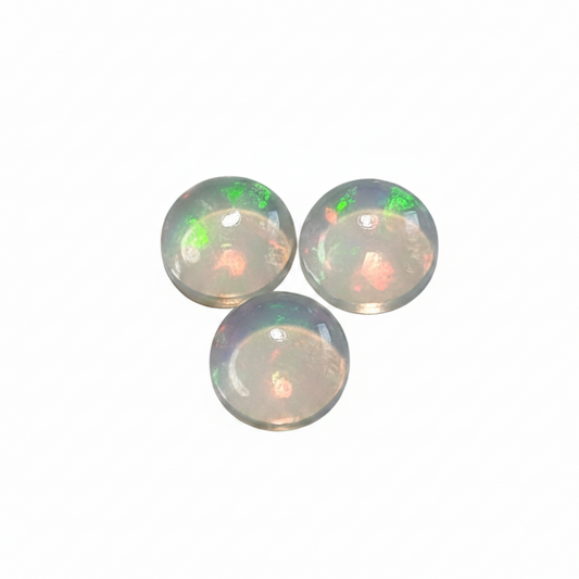Three round cabochon opal gemstones with iridescent green, orange, flashes, displayed on a solid white background.