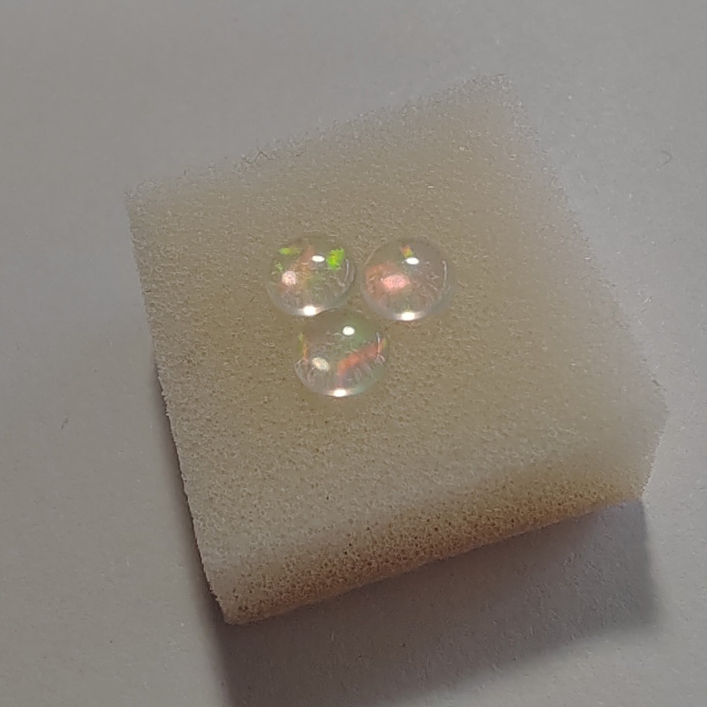Two opal gemstones on a piece of foam with a light gray background
