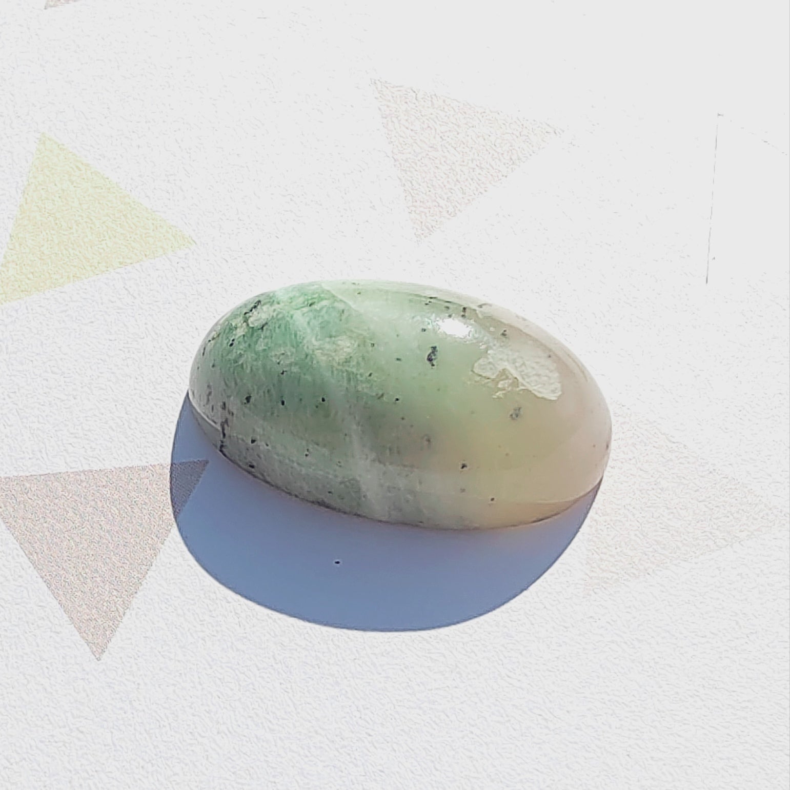 Oval-shaped green stone on a white background