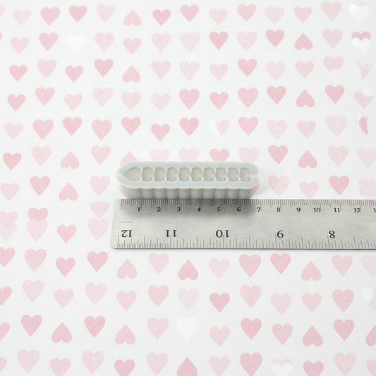 Heart cutter next to a ruler on a white background