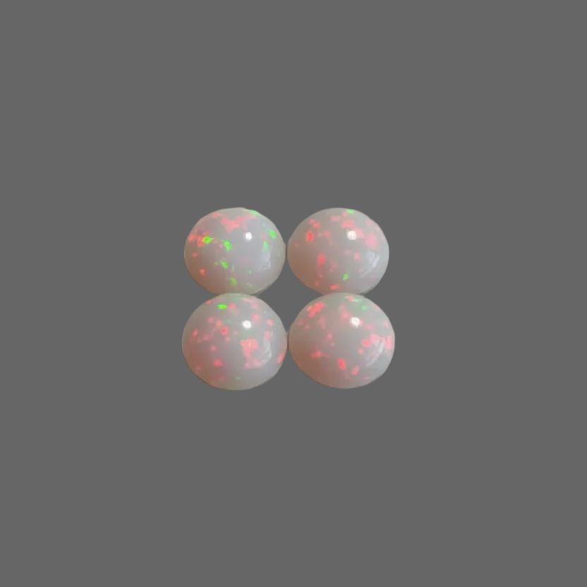 Four round white cabochon gemstones with vibrant pink and green flashes, arranged in a 2x2 grid on a neutral gray background.