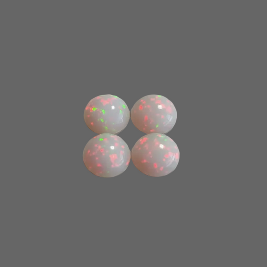 Four round white cabochon gemstones with vibrant pink and green flashes, arranged in a 2x2 grid on a neutral gray background.