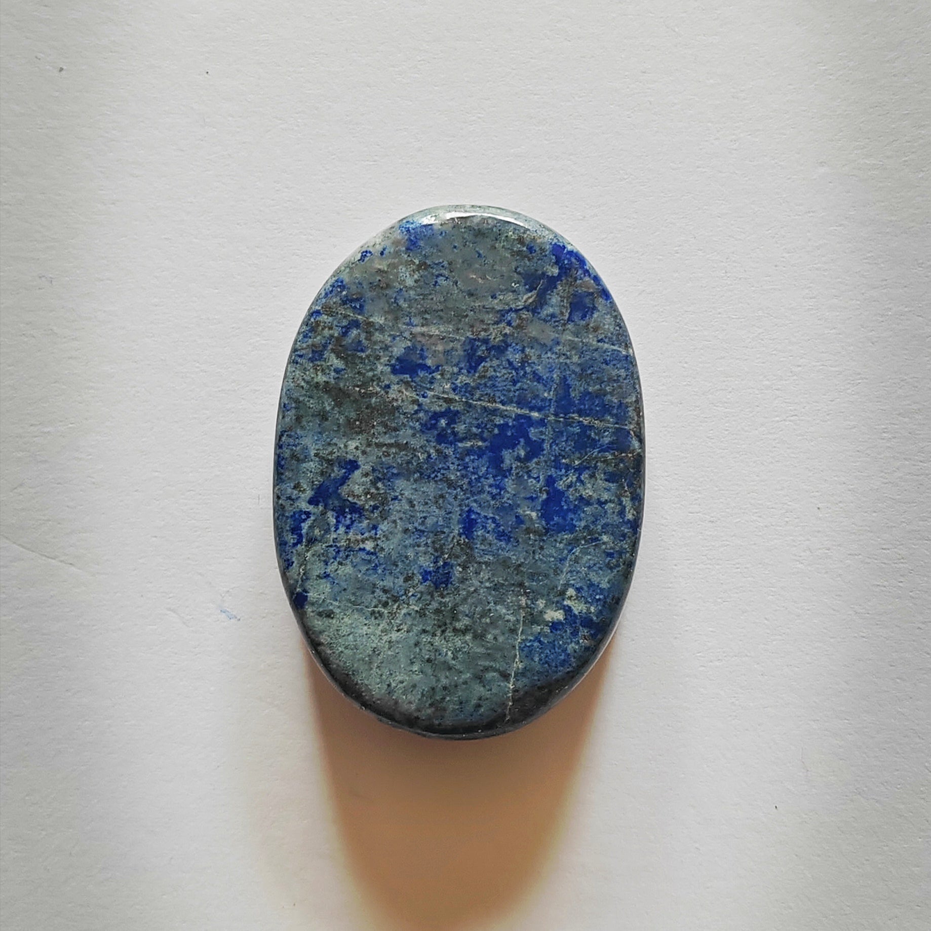 Oval-shaped stone with blue and green patterns on a white background