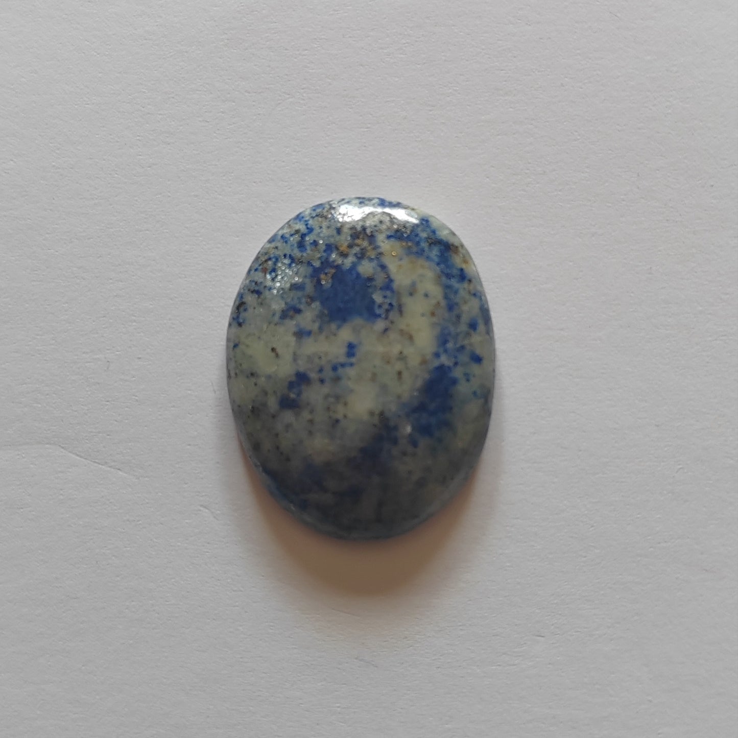 Oval-shaped stone with blue and white speckled pattern on a light gray background