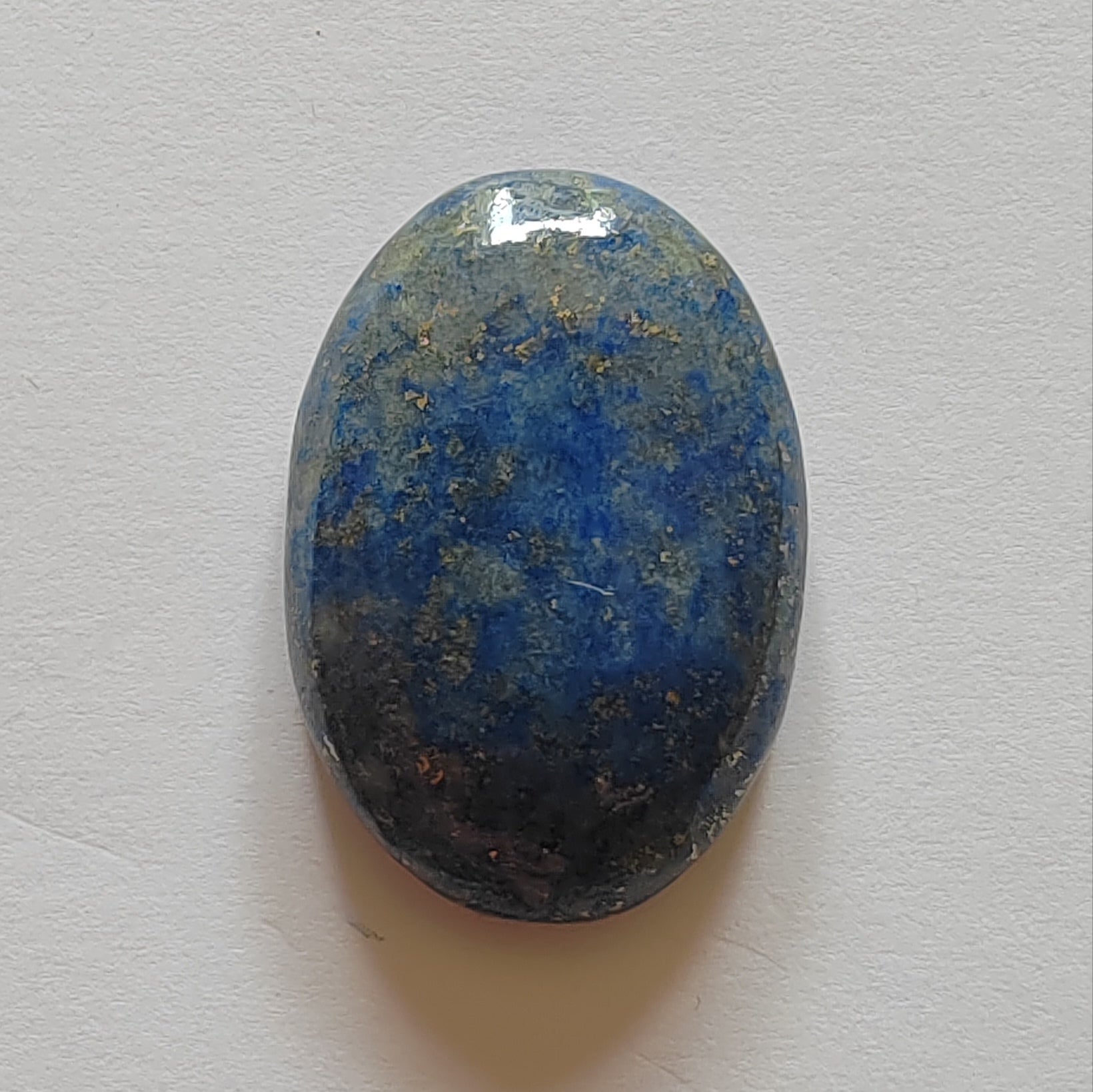 Oval-shaped blue stone on a light grey background