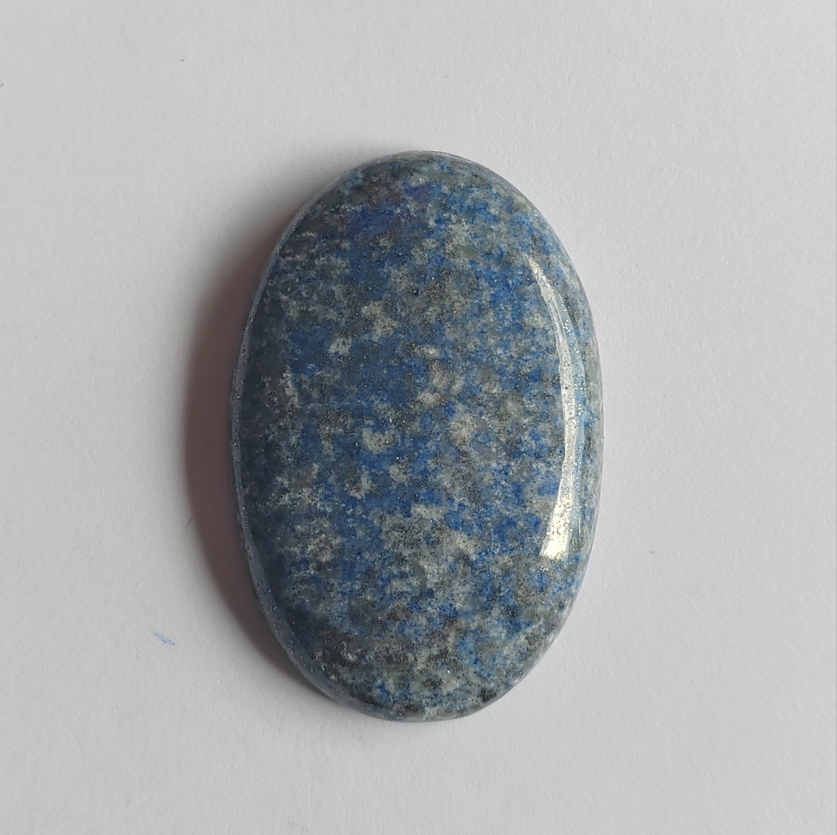 Oval-shaped stone with blue and gray speckled pattern on a light gray background