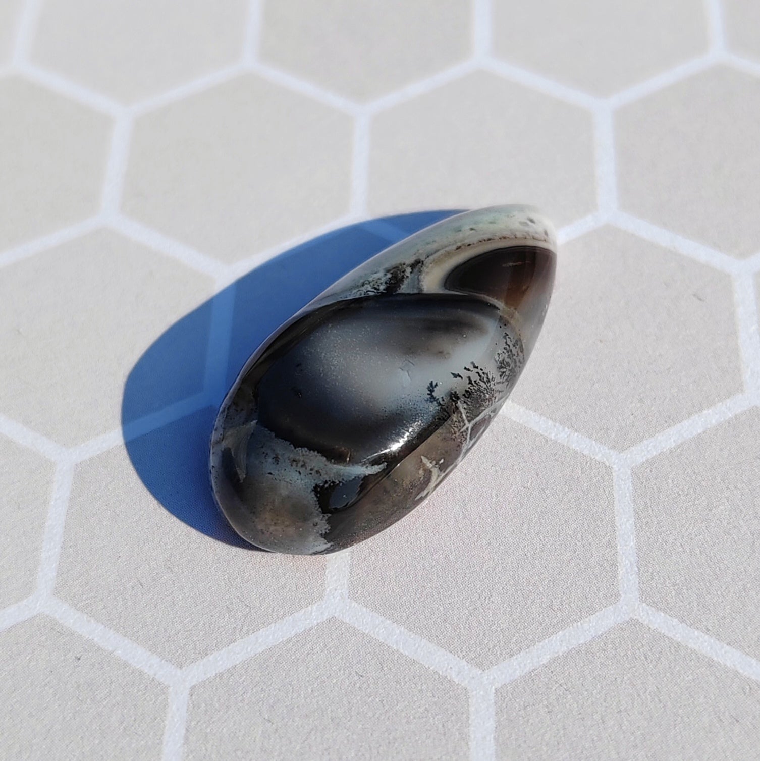 Dendrite stone with blue base on a geometric background.