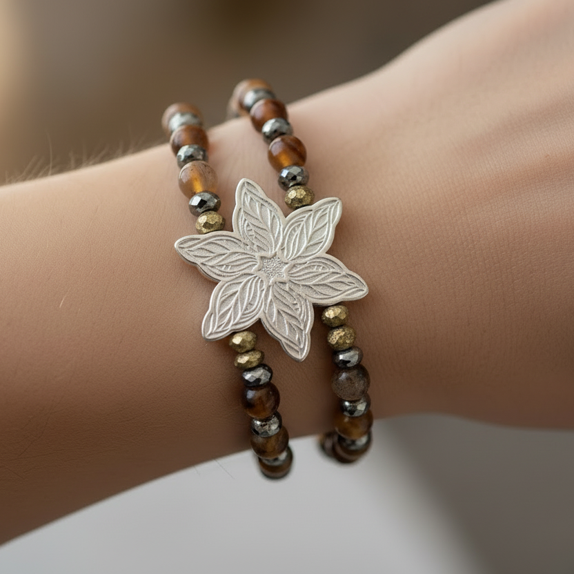 Bracelet with a silver leaf charm on a wrist against a neutral background
