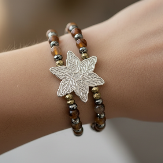 Bracelet with a silver leaf charm on a wrist against a neutral background