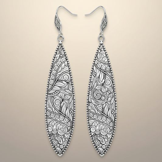 Pair of silver earrings with intricate black floral patterns on a white background