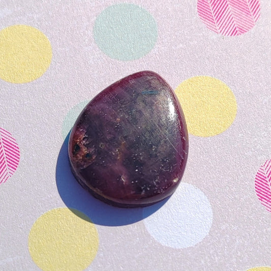 Polished purple stone on a polka dot background