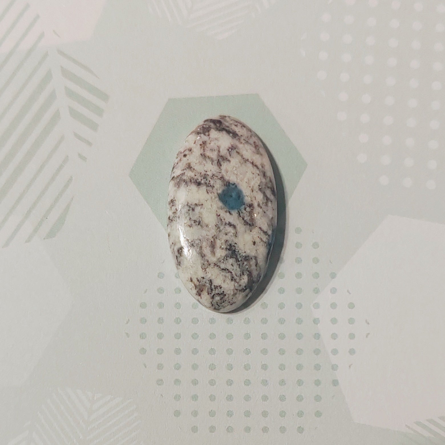 Oval-shaped stone with marbled pattern on a textured white background