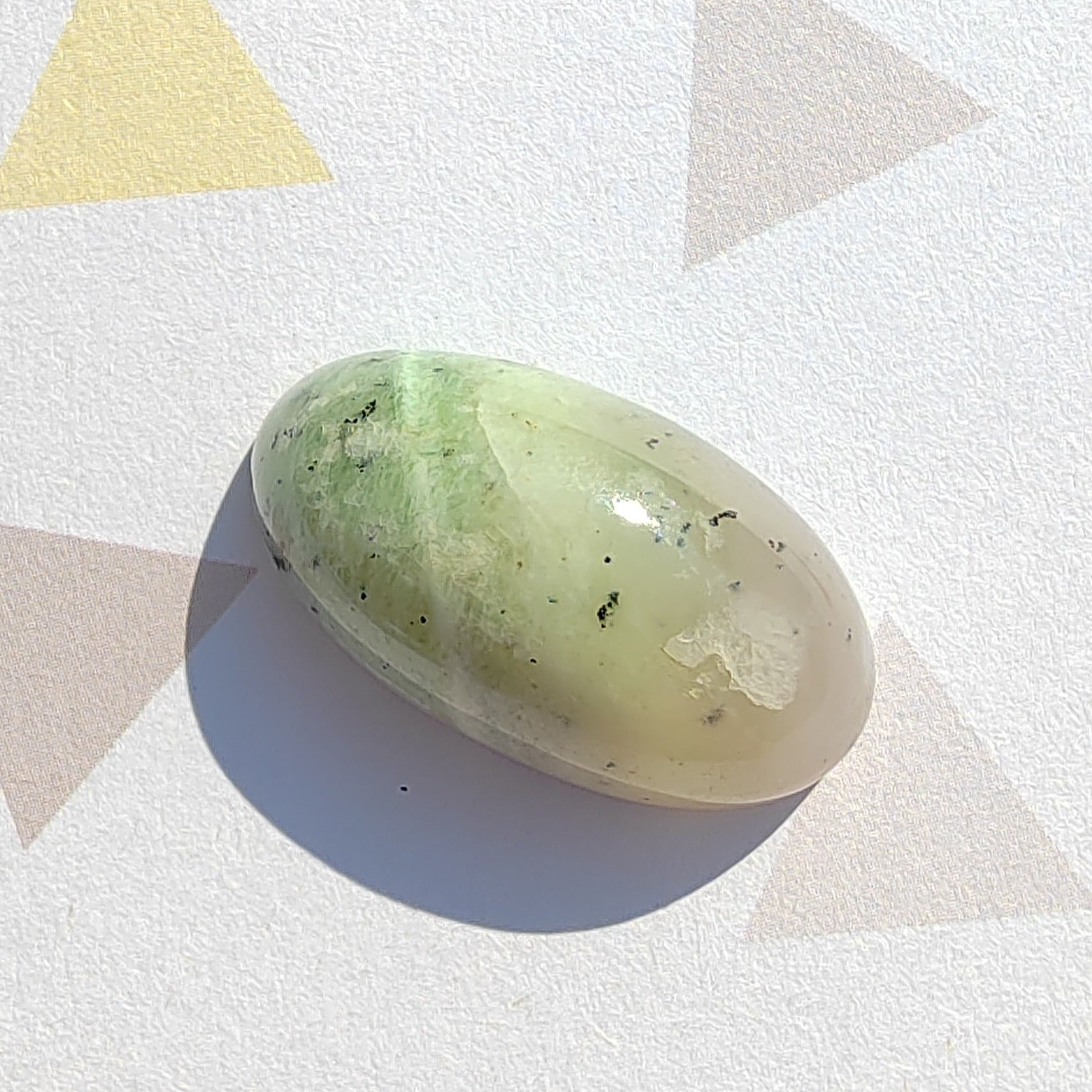 Green stone on a white surface with geometric shapes