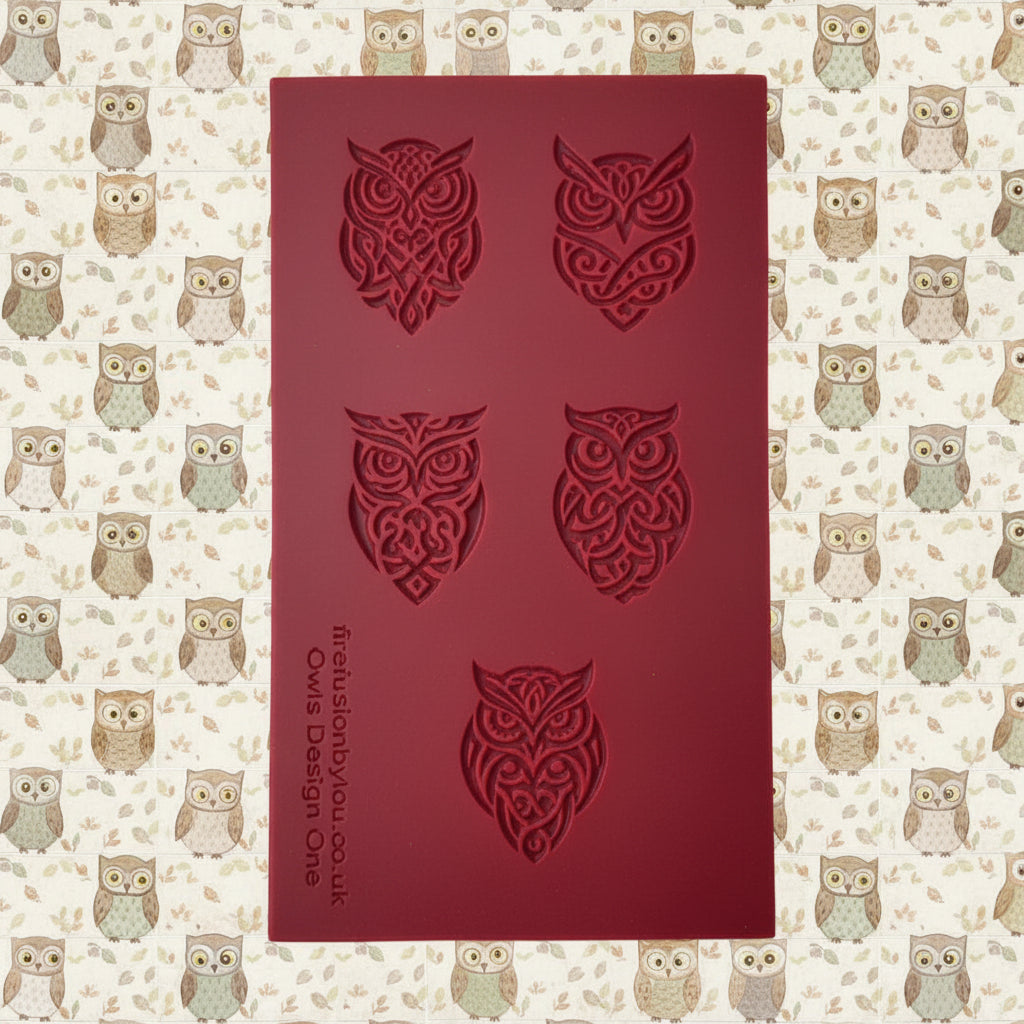 A dark grey rectangular rubber stamp with five debossed owl designs, displayed on a lilac background.
