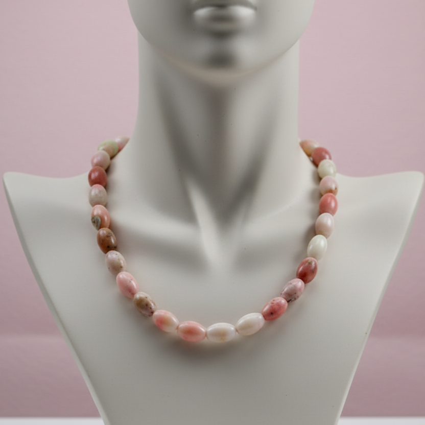 Necklace with pink and white beads on a mannequin against a pink background