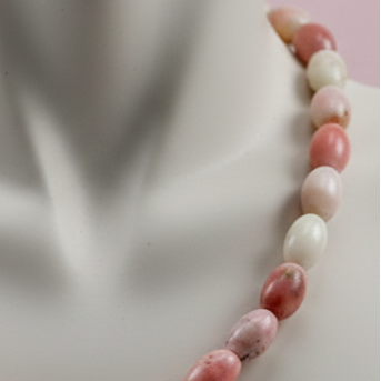 Necklace with pink and white beads on a mannequin bust.