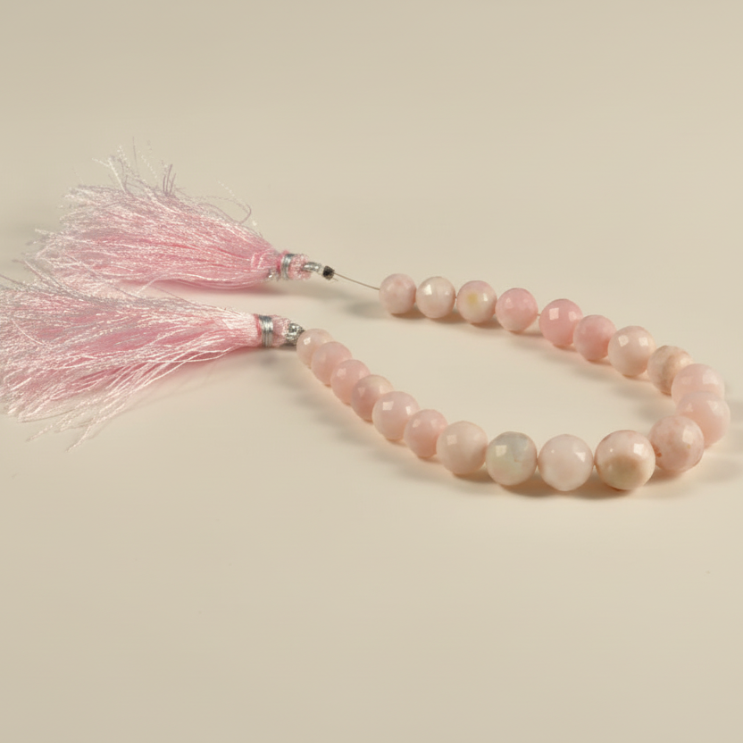 Pink beaded bracelet with tassel on a beige background