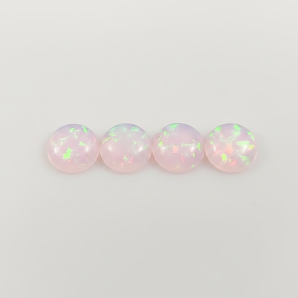 Four round opal stones with a pinkish hue on a light gray background