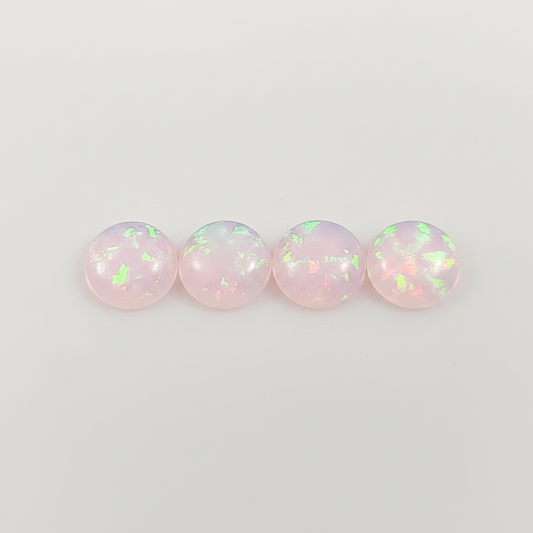 Four round opal stones with a pinkish hue on a light gray background