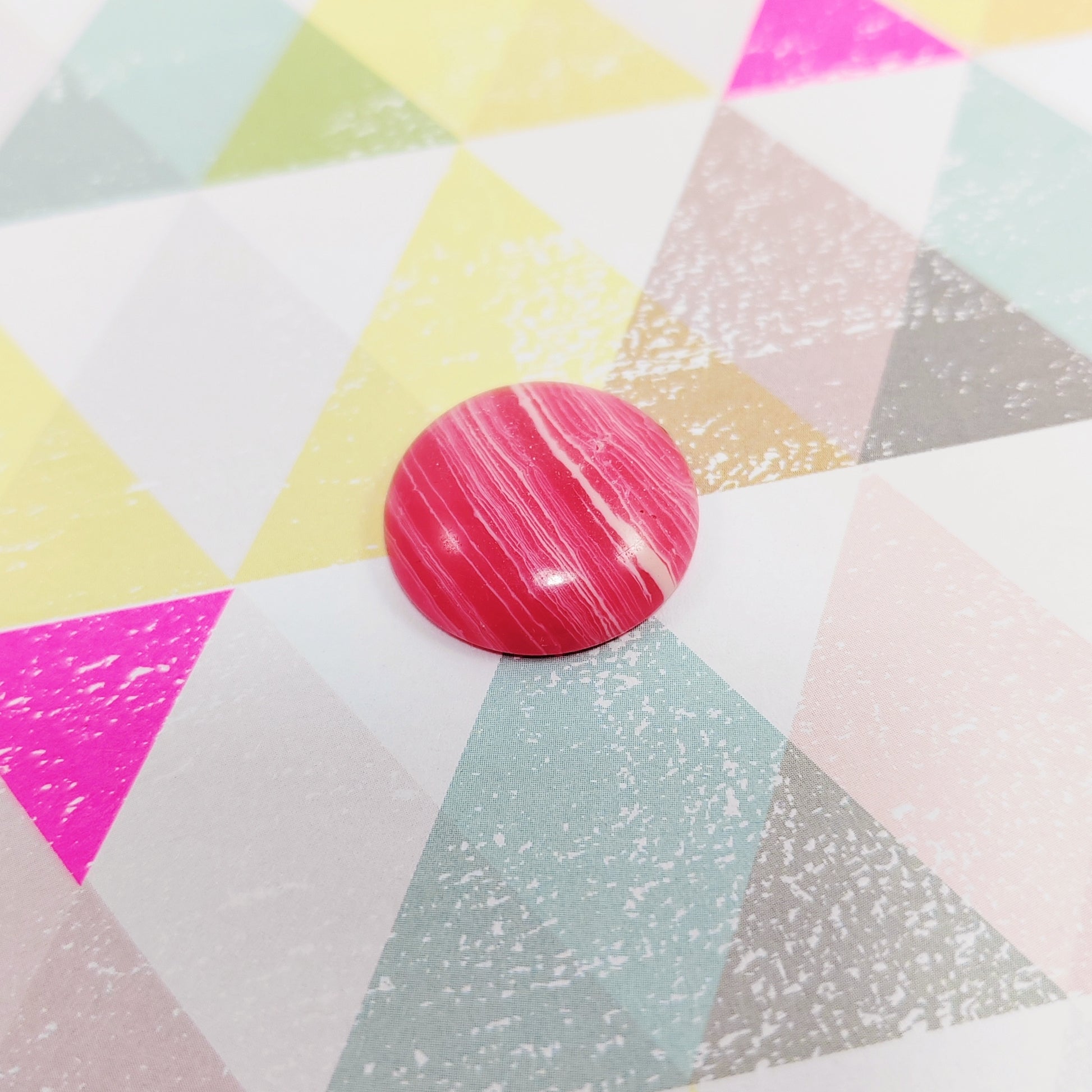 Pink marbled agate on a colourful geometric patterned surface