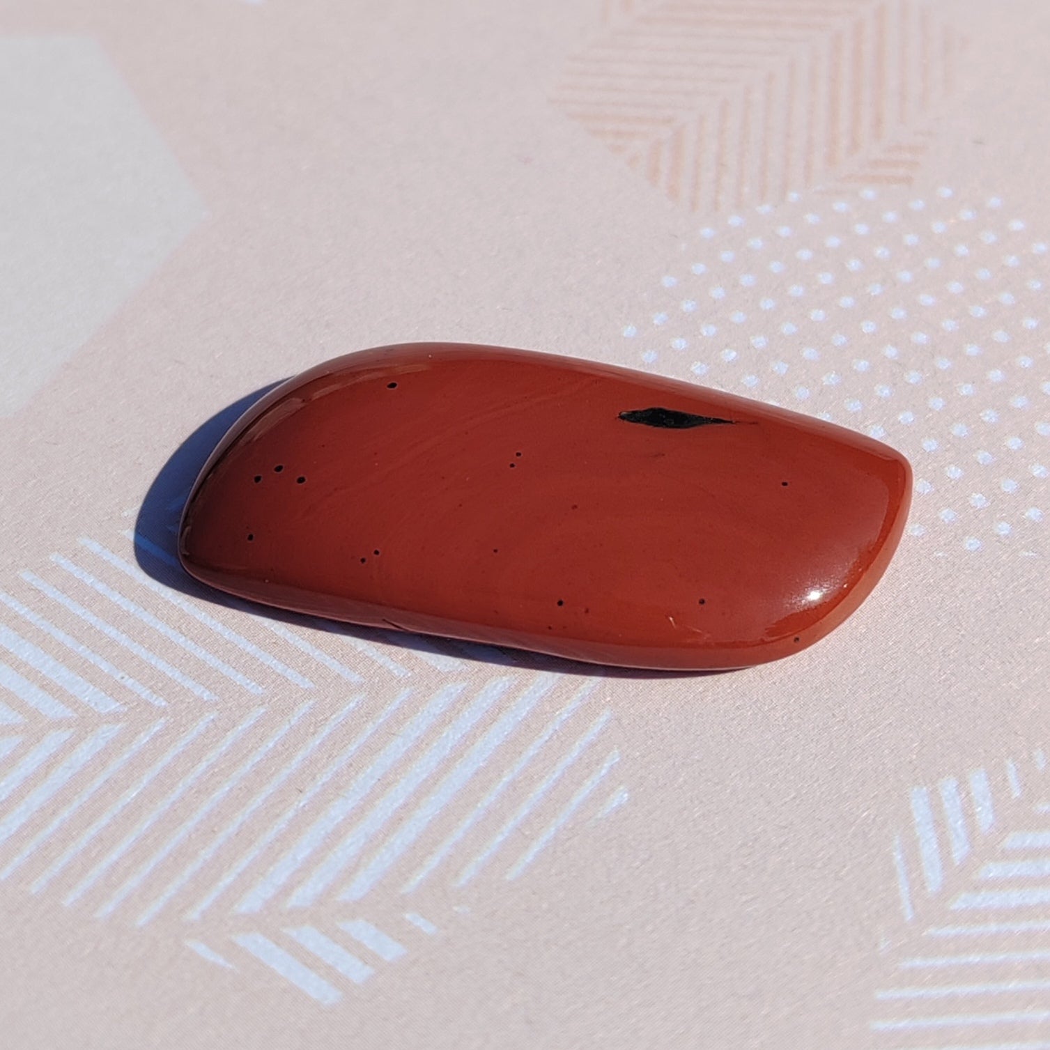 Red jasper cabochon on a patterned surface