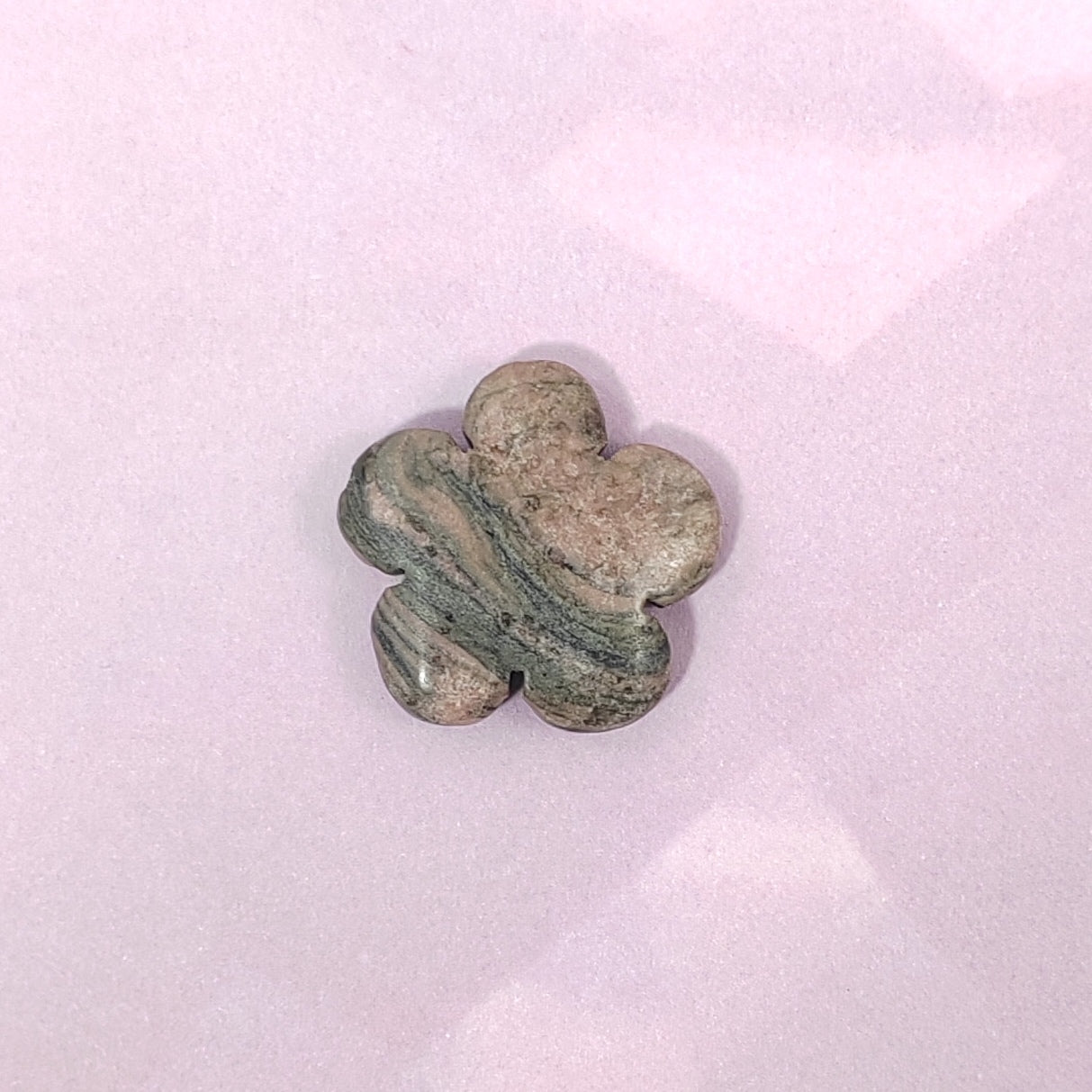Flower-shaped stone on a light pink background