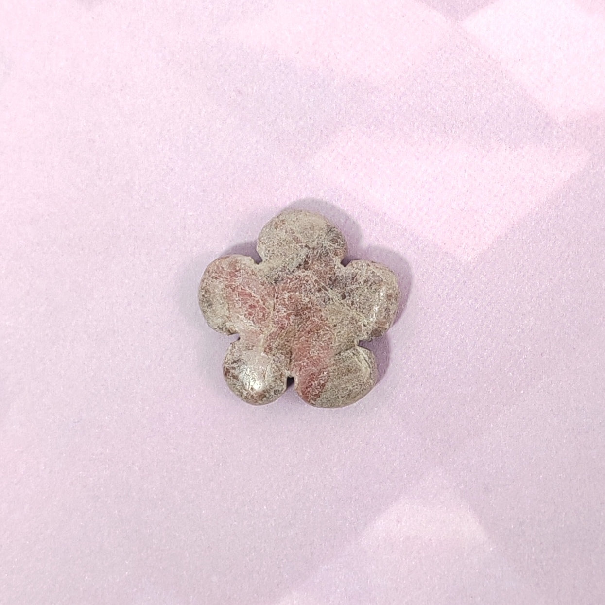Flower-shaped stone on a pink fabric background