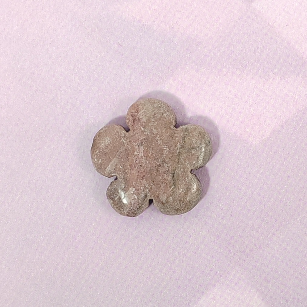 Metallic flower-shaped object on a pink textured background