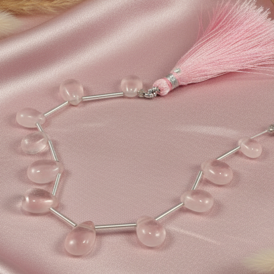 Necklace with pink beads and a tassel on a pink satin background