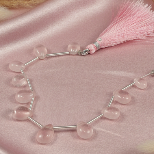 Necklace with pink beads and a tassel on a pink satin background