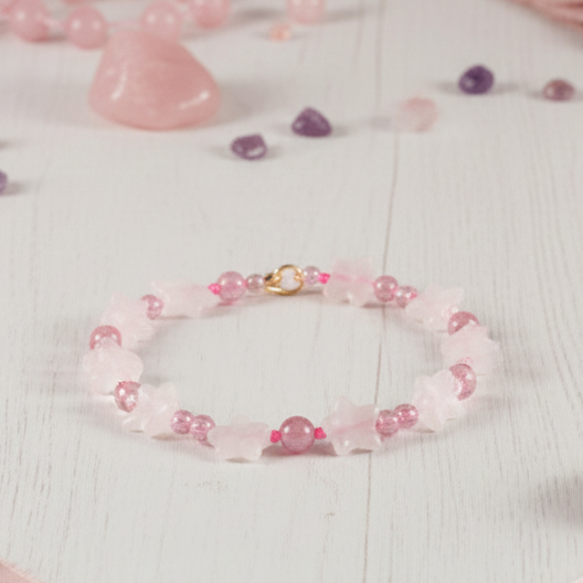 Pink beaded bracelet on a white surface with small decorative items around