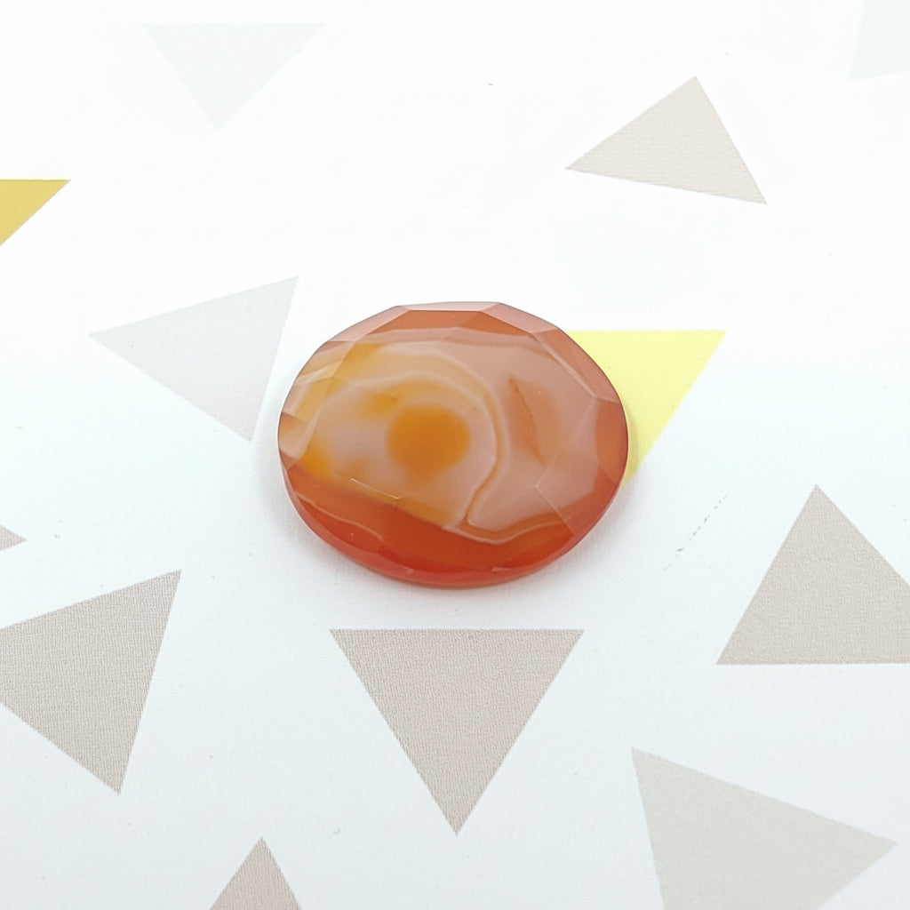 Round orange and white stone on a patterned background
