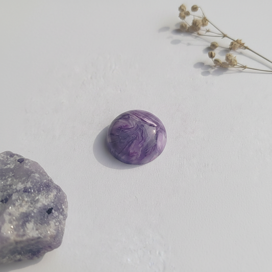 Purple charoite on a light background with dried flowers.