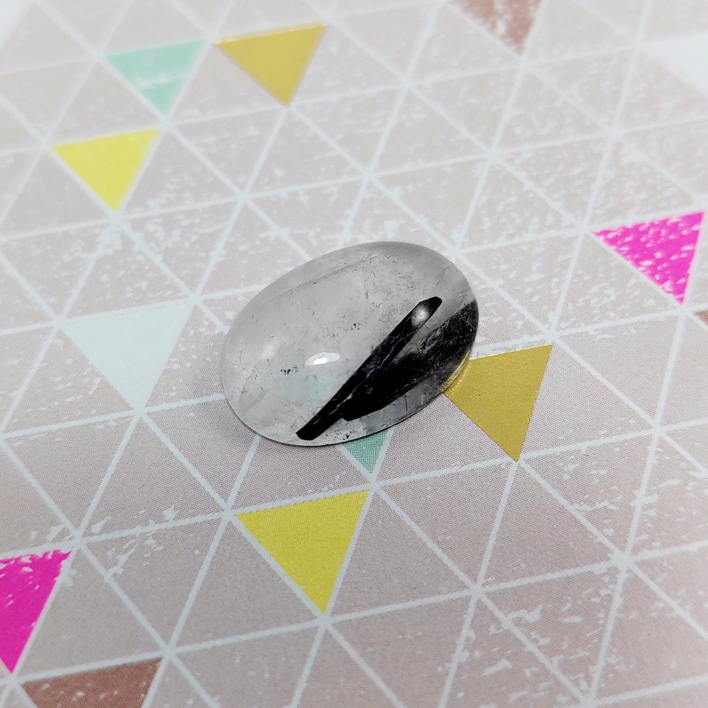 Rutilated quartz on a geometric-patterned surface with colourful triangles
