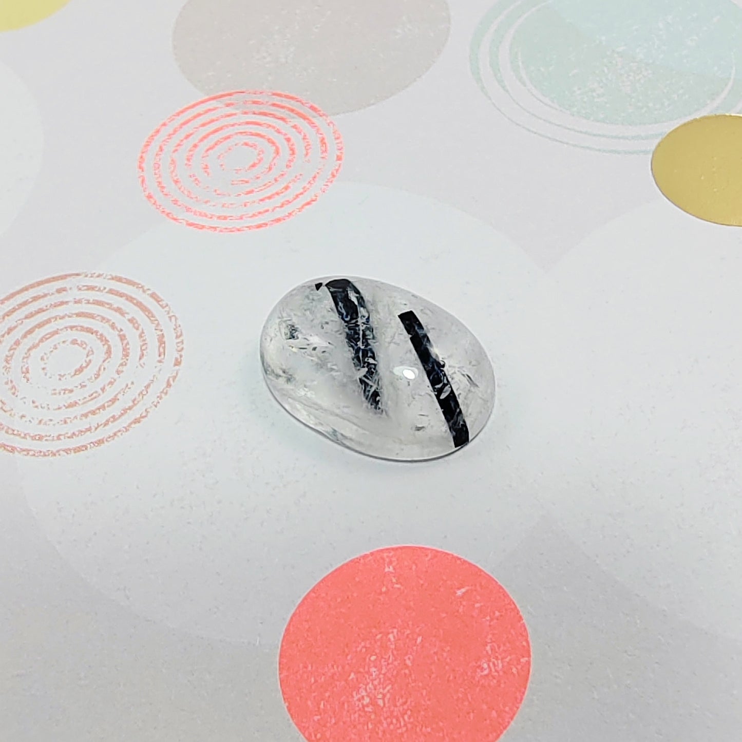 Clear stone with black stripe on a white background with colorful circular patterns
