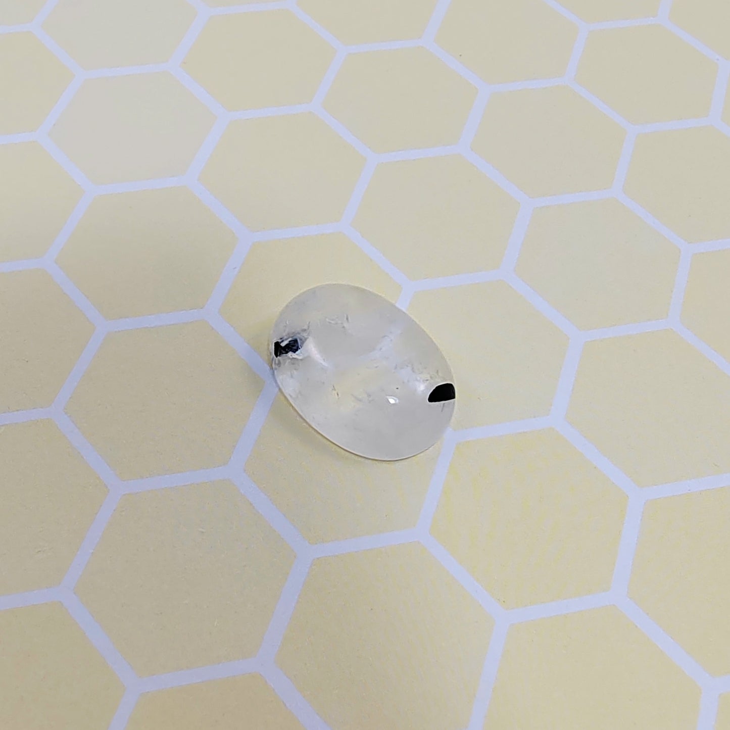 Rutilated quartz with black accents on a light hexagonal patterned surface