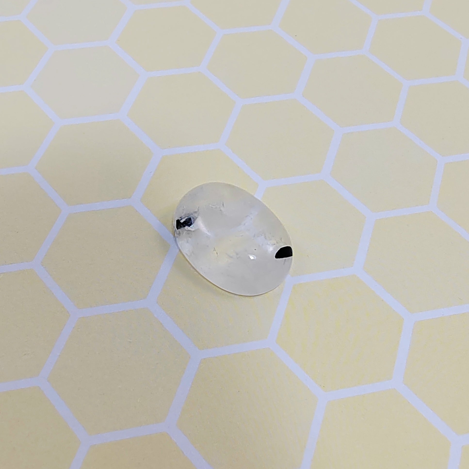 Rutilated quartz with black accents on a light hexagonal patterned surface