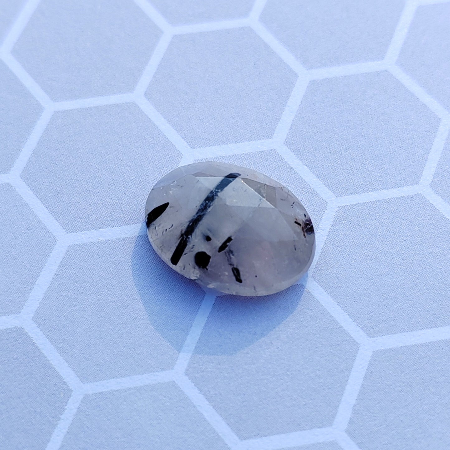 Faceted gemstone on a light blue honeycomb patterned surface