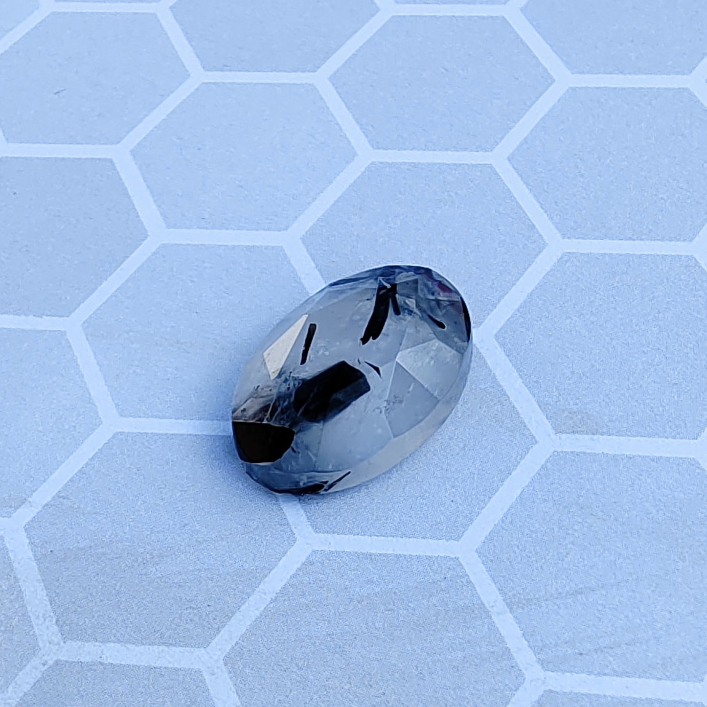 Faceted gemstone on a light blue honeycomb patterned surface
