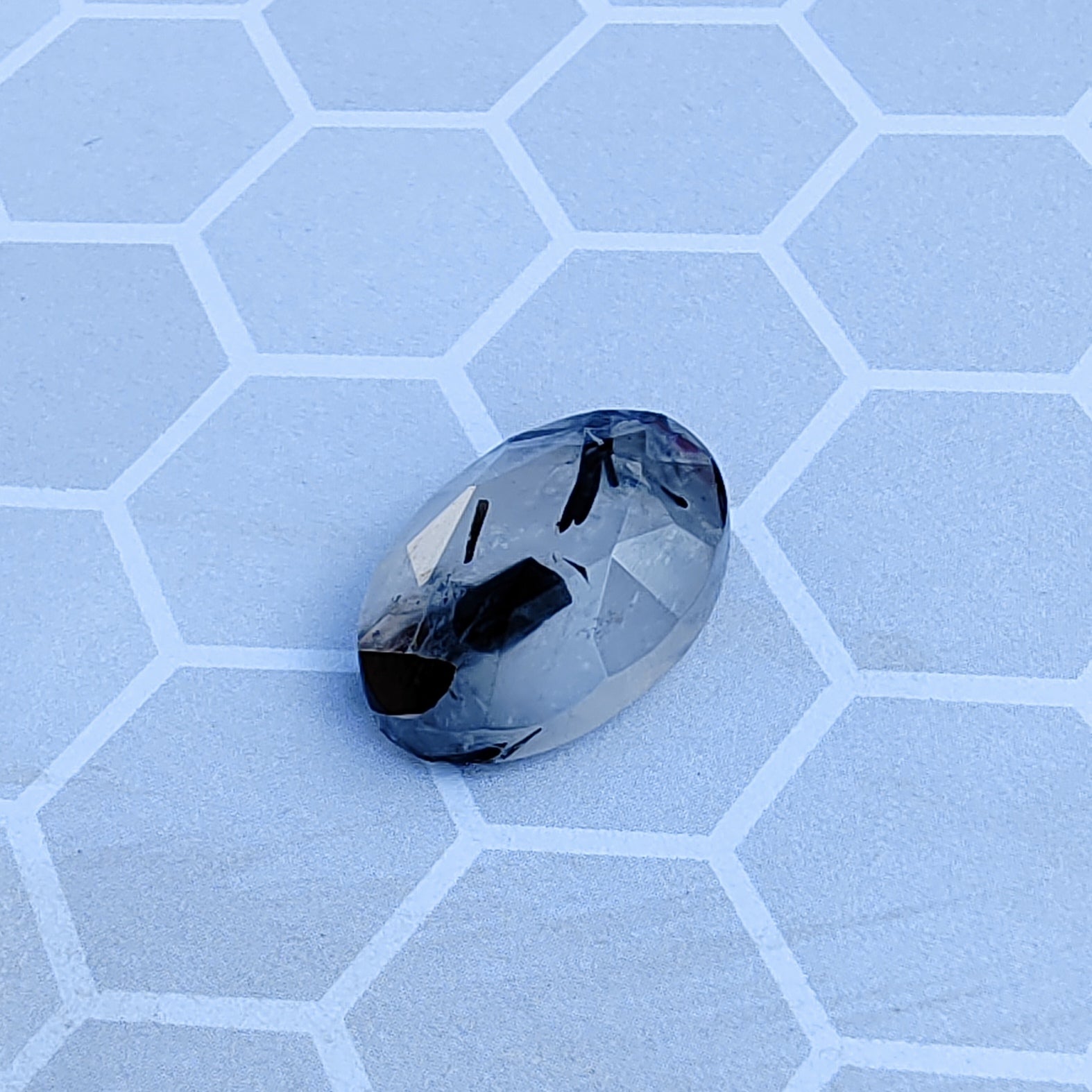 Faceted gemstone on a light blue honeycomb patterned surface