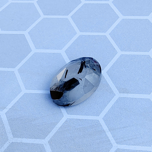 Faceted gemstone on a light blue honeycomb patterned surface