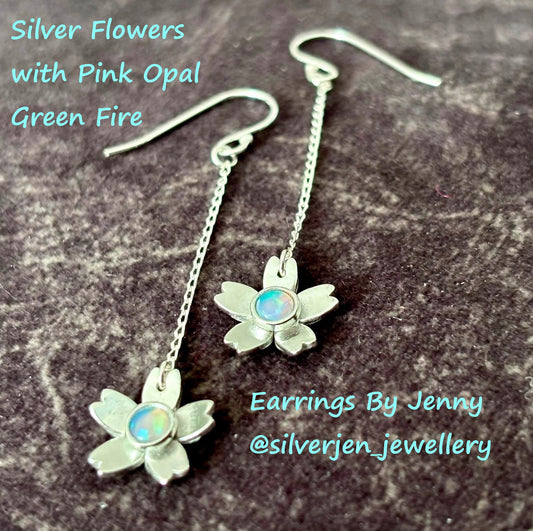 Silver flower drop earrings with pink opal centers, displayed on a dark textured surface with text overlays reading 'Silver Flowers with Pink Opal Green Fire' and 'Earrings By Jenny @silverjen_jewellery'.