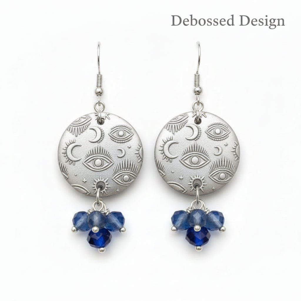 A small mystical eye repeat pattern embossed In silver dangly earrings with beads.