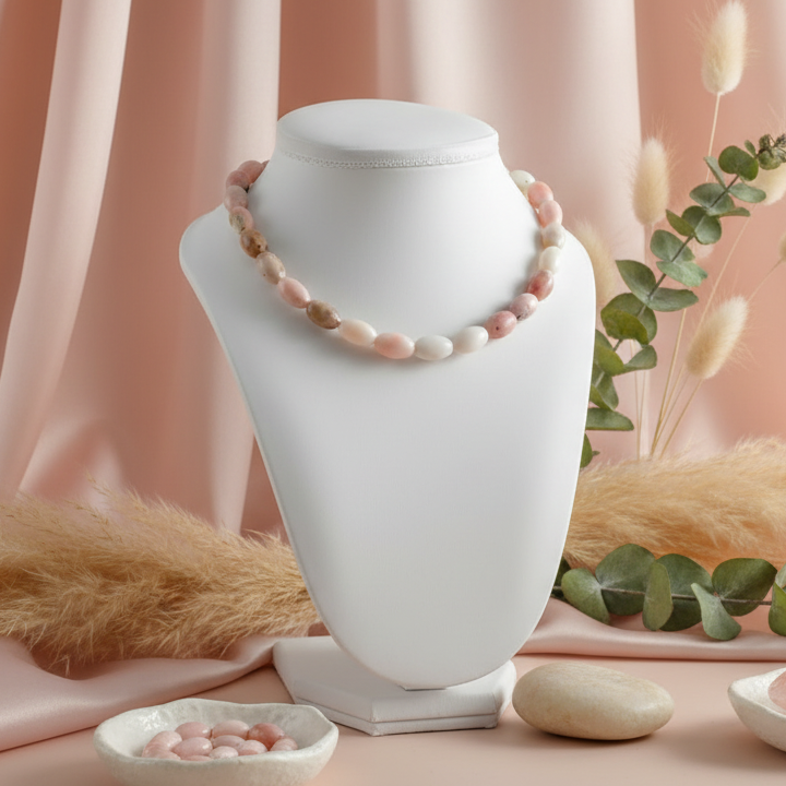 Necklace on a white stand with decorative elements on a pink background