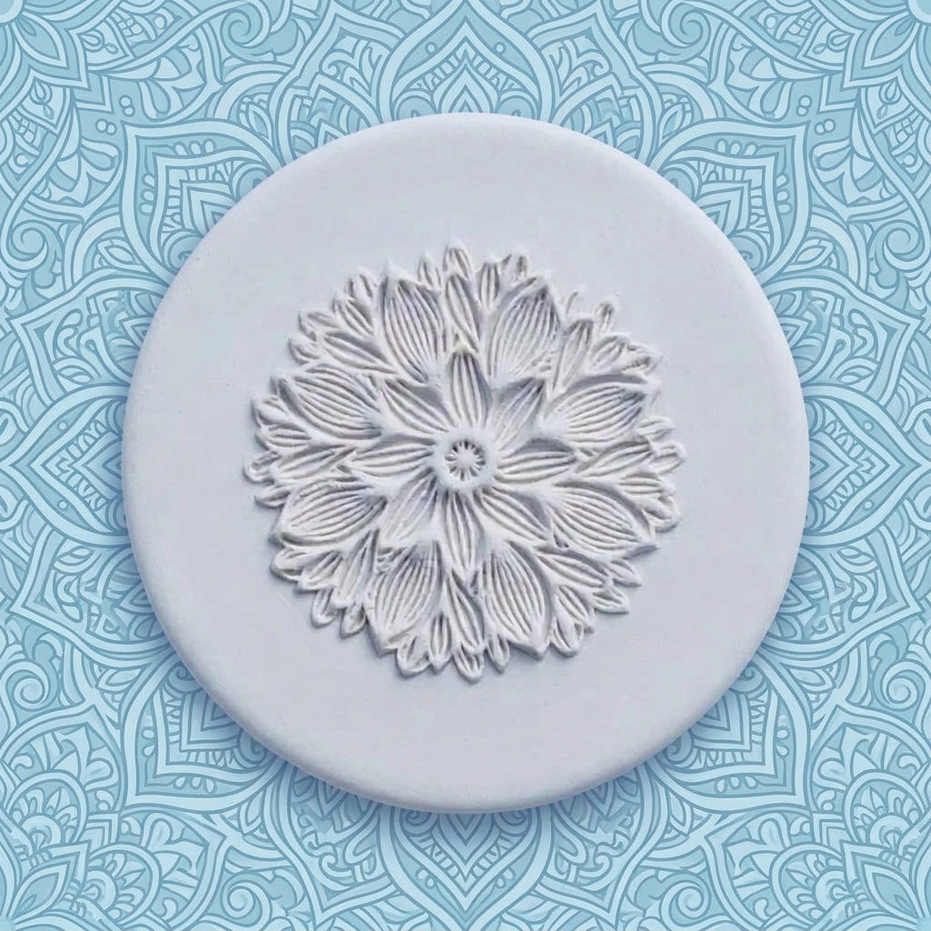 A round, clay stamp featuring an embossed floral mandala design, shown on a light blue background.