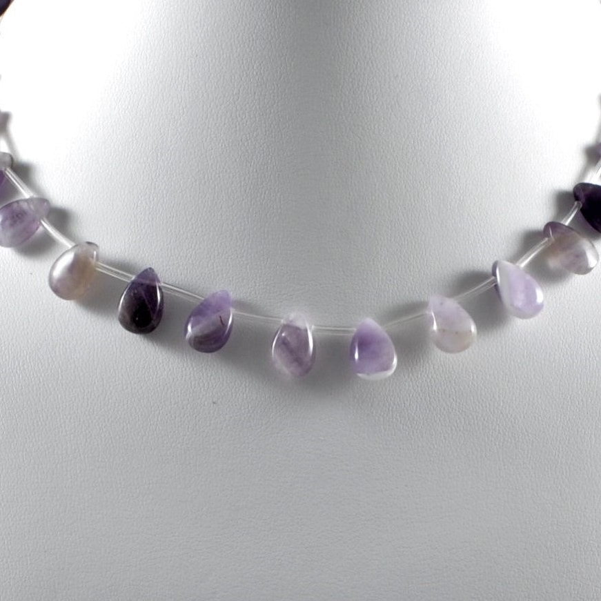 Necklace with purple and white beads on a light gray background