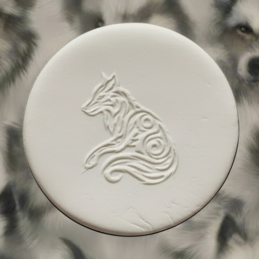 A round clay embossed wolf design embossed in clay, using a rubber texture mat called sitting wolf designs.