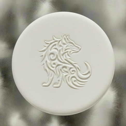 A round clay embossed wolf design embossed in clay, using a rubber texture mat called sitting wolf designs.