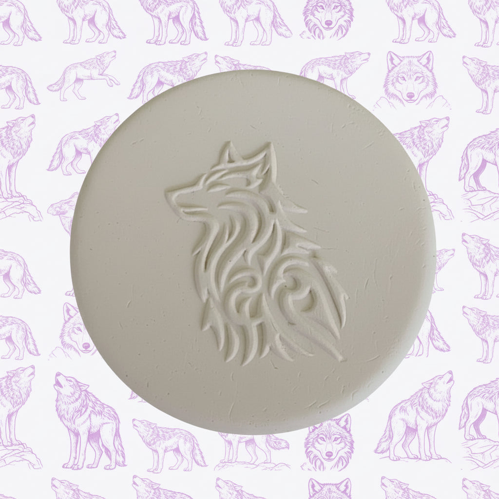 A round clay embossed wolf design embossed in clay, using a rubber texture mat called sitting wolf designs.