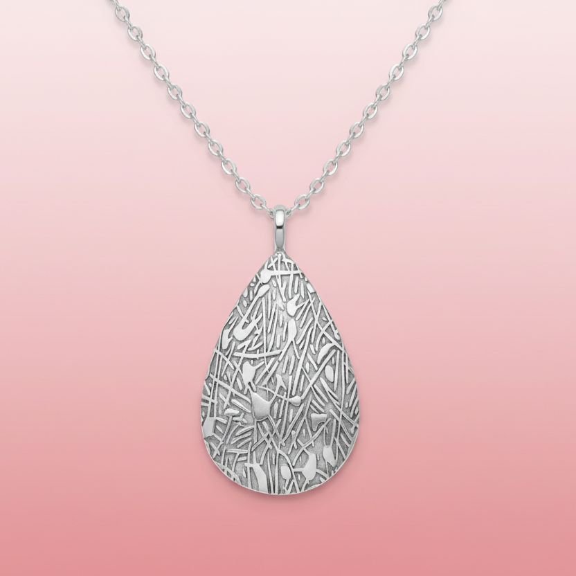 Silver teardrop-shaped pendant with intricate design on a white background
